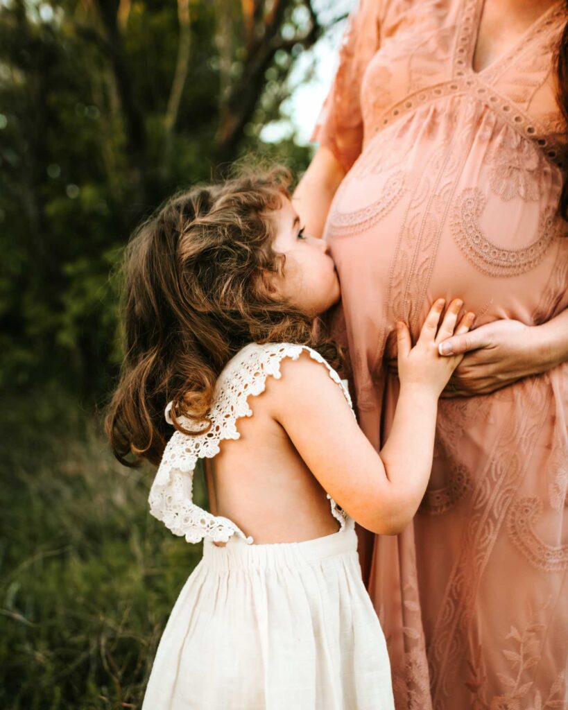 Du bist wie deine Mutter: Mutter-Tochter-Beziehungen beginnen bereits im Babybauch, den das kleine Schwesterchen im Bild hier küsst und herzt.