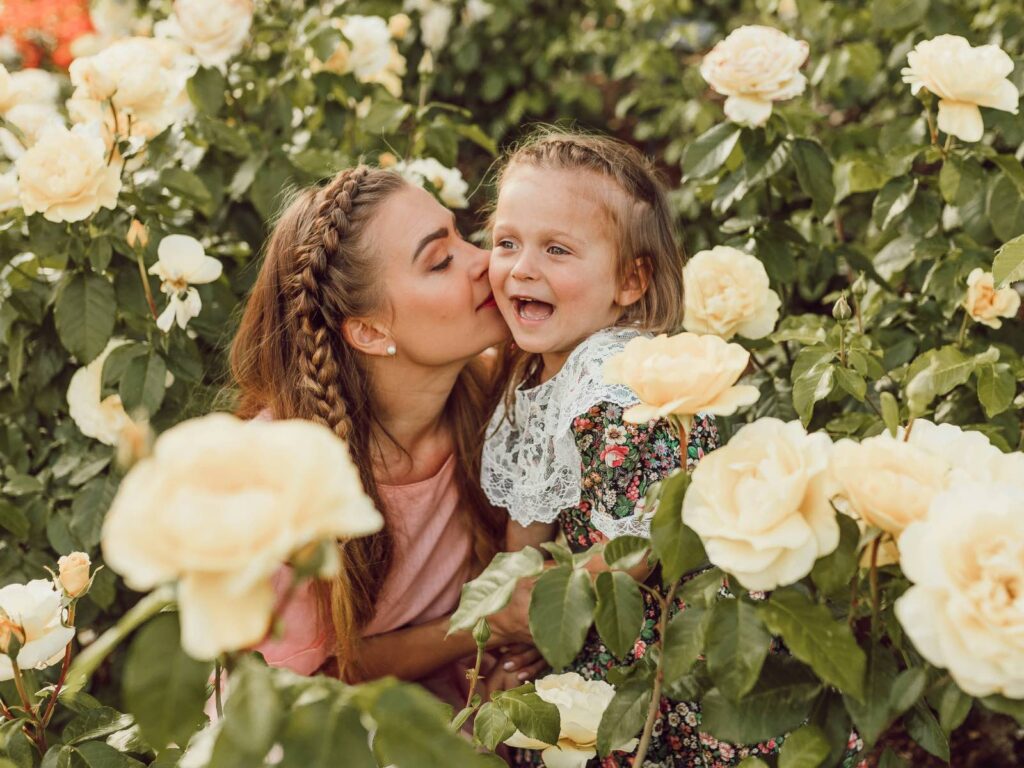Du bist wie deine Mutter: Mutter-Tochter-Beziehungen bilden sich im Lauf der Kindheit: Mama-Medizin ist die beste Medizin wie dieser liebevolle Kuss, den die Mutter ihrem Mädchen im Rosengarten gibt.
