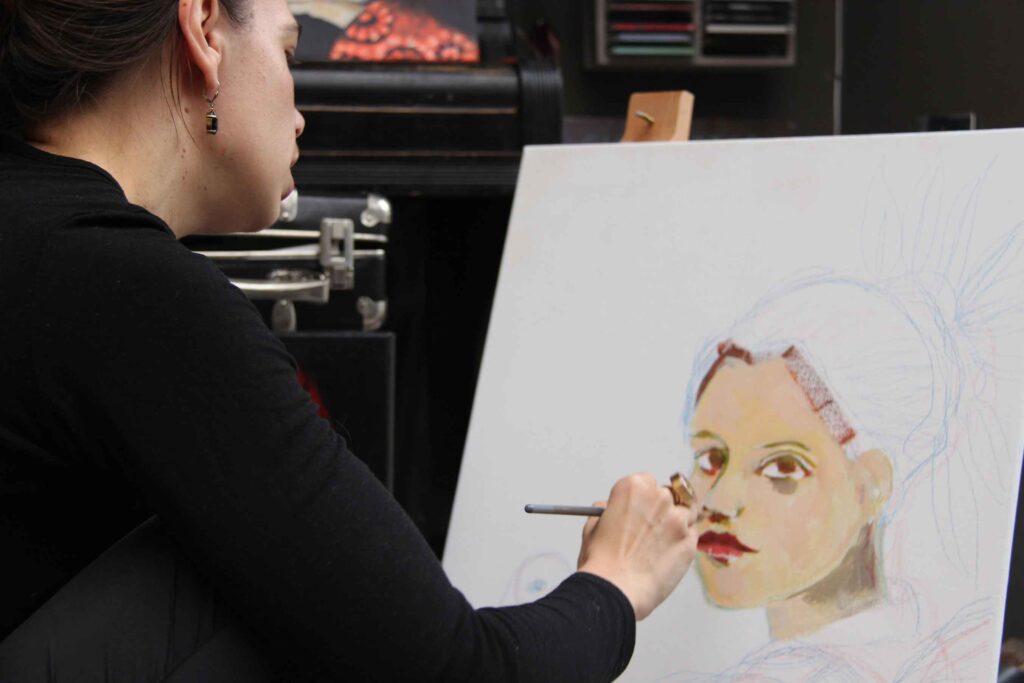 Stephanie Steinhardt malt ein Portrait einer Frau mit neutralem Gesichtsausdruck und ausdrucksstarken Augen.