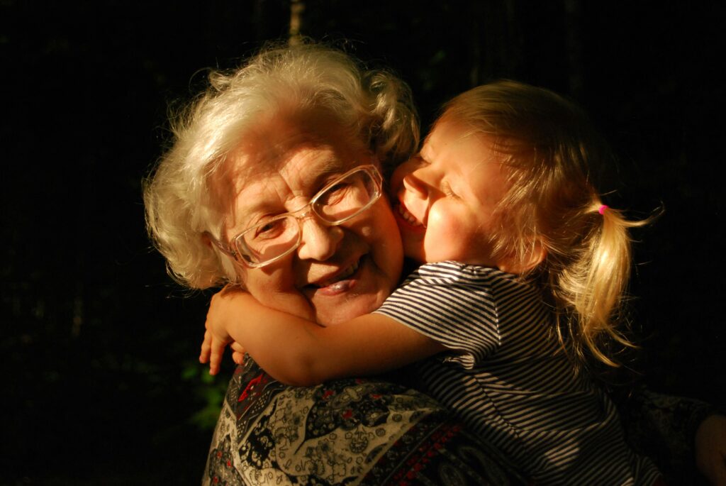 Wie Großmütter die Welt retten können, indem sie in Liebe und Güte Frieden vorleben: dieses Bild zeigt ein kleines Mädchen , die ihre Oma umarmt. Der Blick der beiden ist voller Liebe und Zuneigung.